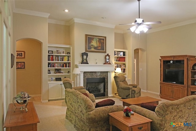 carpeted living room with built in shelves, ceiling fan, and crown molding