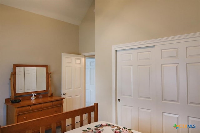 bedroom featuring high vaulted ceiling and a closet