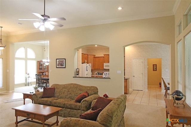 living room with ceiling fan with notable chandelier, light tile patterned flooring, and crown molding