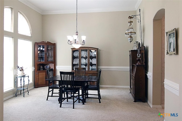 carpeted dining space featuring a chandelier and ornamental molding