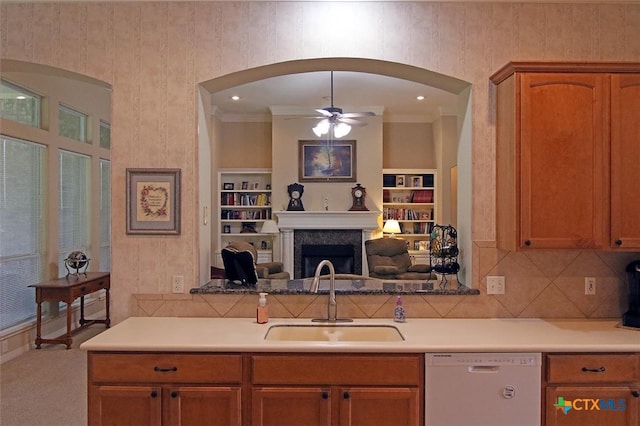 kitchen with white dishwasher, built in shelves, carpet floors, sink, and ceiling fan