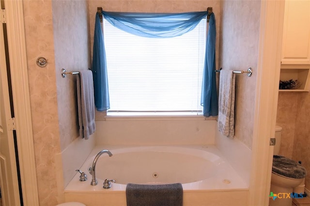 bathroom with a tub to relax in and toilet