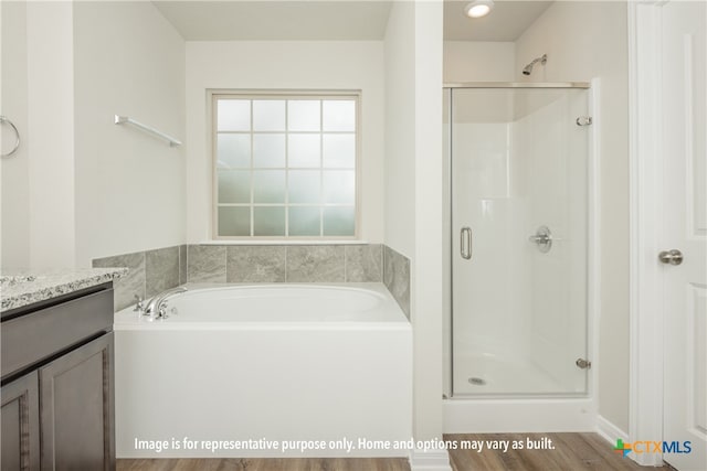 bathroom featuring hardwood / wood-style flooring, vanity, and plus walk in shower