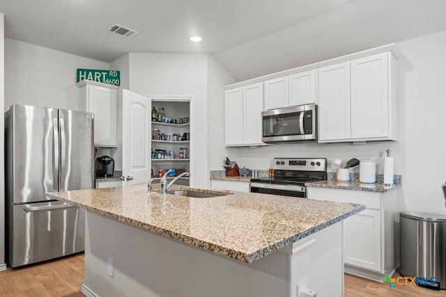 kitchen with a center island with sink, white cabinetry, stainless steel appliances, and light hardwood / wood-style flooring