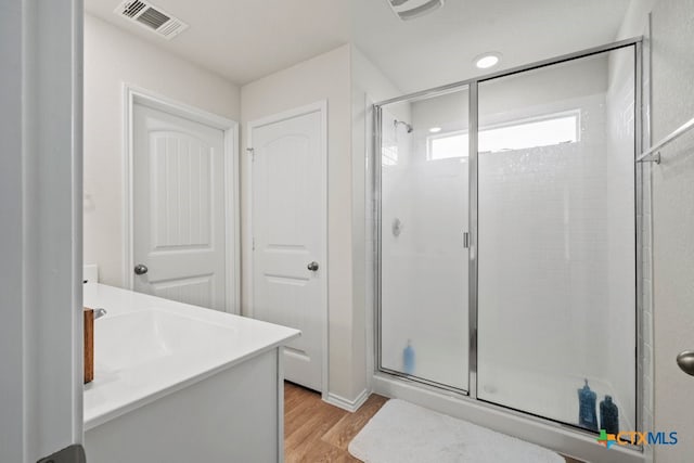 bathroom with hardwood / wood-style floors, vanity, and a shower with shower door