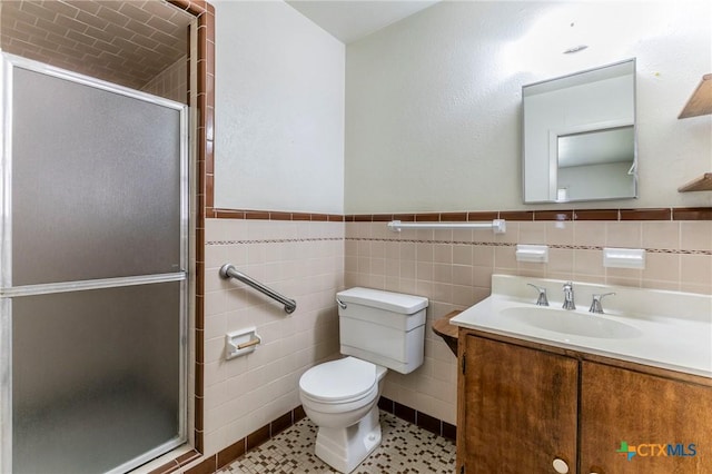 full bath with tile walls, toilet, vanity, a stall shower, and wainscoting