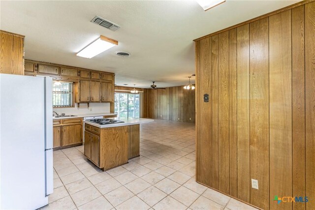 kitchen with light countertops, freestanding refrigerator, black gas cooktop, brown cabinets, and visible vents