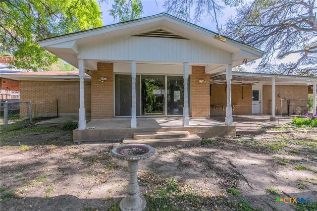 back of property featuring brick siding, fence, and a patio