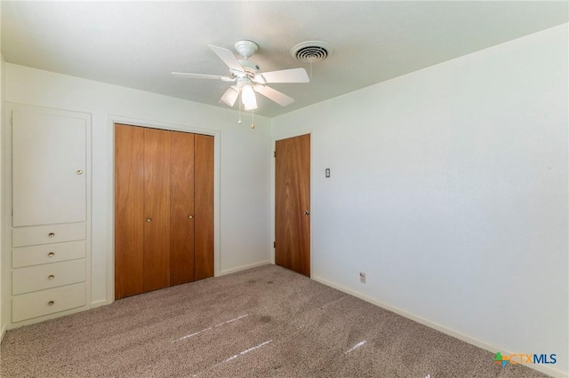 unfurnished bedroom with a closet, carpet floors, ceiling fan, and visible vents