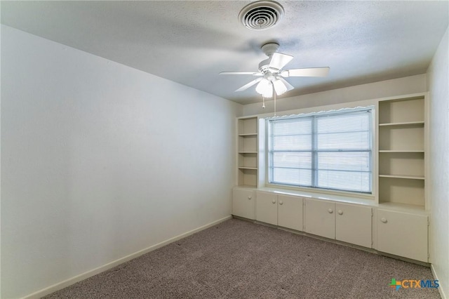 empty room with light colored carpet, visible vents, ceiling fan, and a textured ceiling