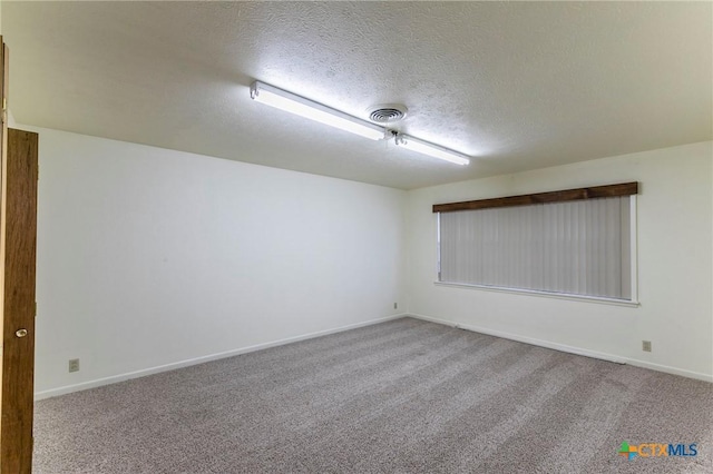 carpeted spare room featuring baseboards, visible vents, and a textured ceiling