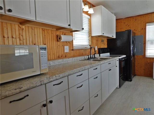 kitchen featuring wood walls, white cabinets, sink, and electric range