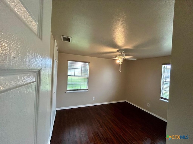 empty room with dark wood-type flooring, a textured ceiling, and ceiling fan