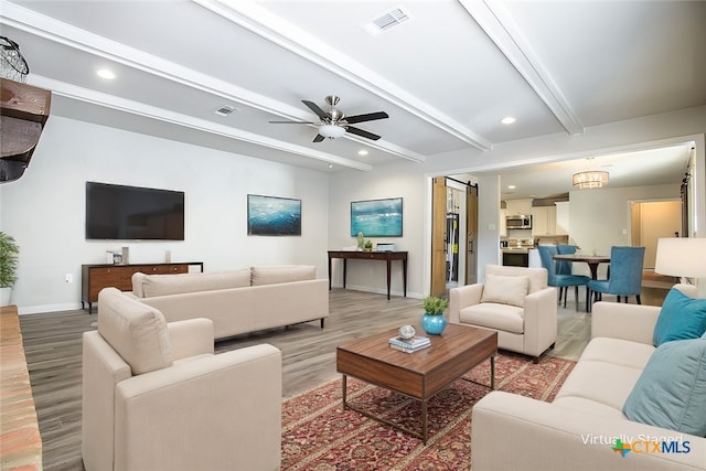 living room featuring a barn door, wood-type flooring, ceiling fan, and beam ceiling