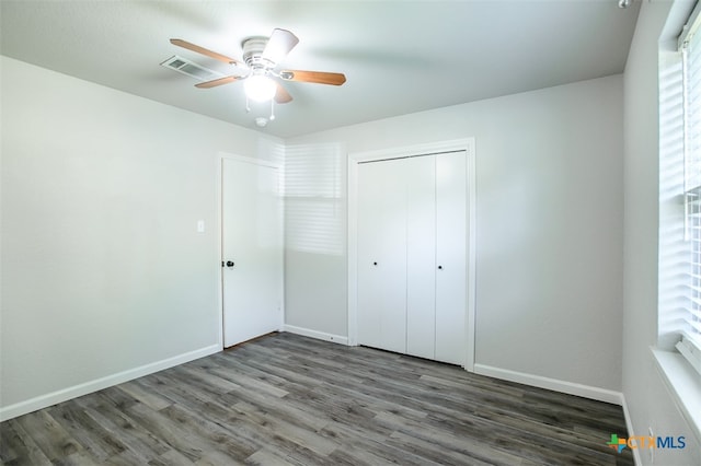 unfurnished bedroom with dark hardwood / wood-style floors, ceiling fan, and a closet