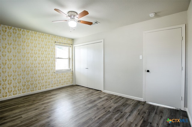 unfurnished bedroom featuring a textured ceiling, ceiling fan, dark hardwood / wood-style floors, and a closet