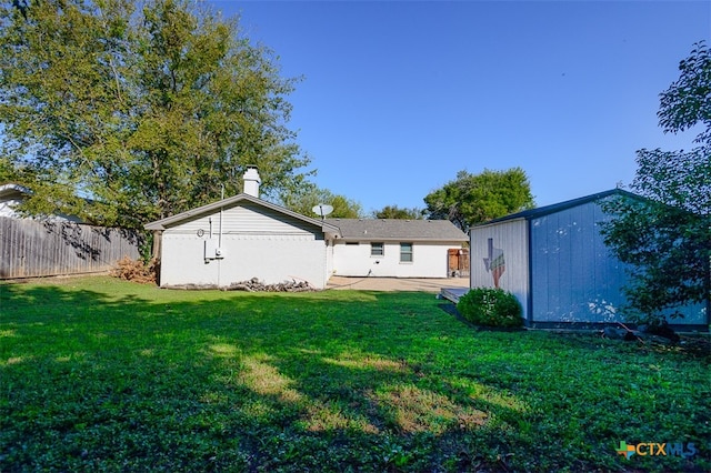 back of house with a storage unit and a yard