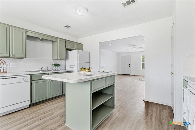 kitchen with white appliances, a center island, light wood-type flooring, and green cabinets