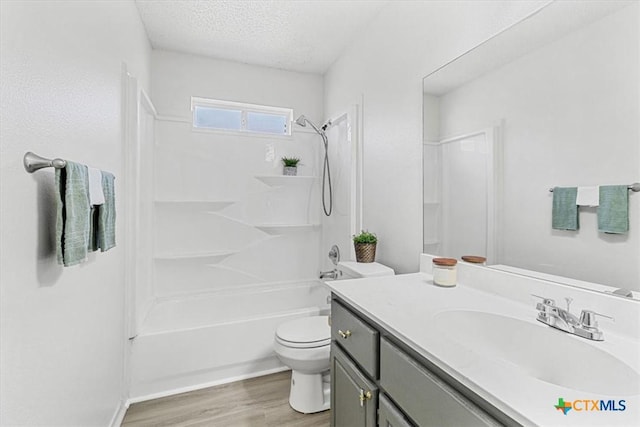 full bathroom with a textured ceiling, toilet, wood-type flooring, shower / bathing tub combination, and vanity