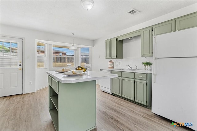 kitchen with white appliances, a center island, hanging light fixtures, green cabinets, and sink