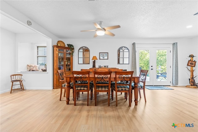 dining area with light wood-type flooring, a textured ceiling, and ceiling fan