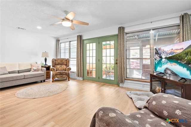 living room with a textured ceiling, light hardwood / wood-style floors, and ceiling fan