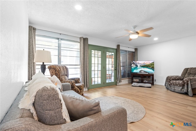 living room with ceiling fan, wood-type flooring, and a textured ceiling