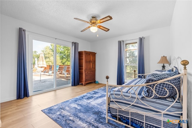 bedroom featuring a textured ceiling, hardwood / wood-style floors, access to outside, and ceiling fan