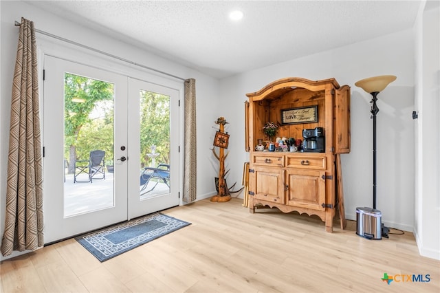 doorway featuring light hardwood / wood-style floors, a textured ceiling, and french doors