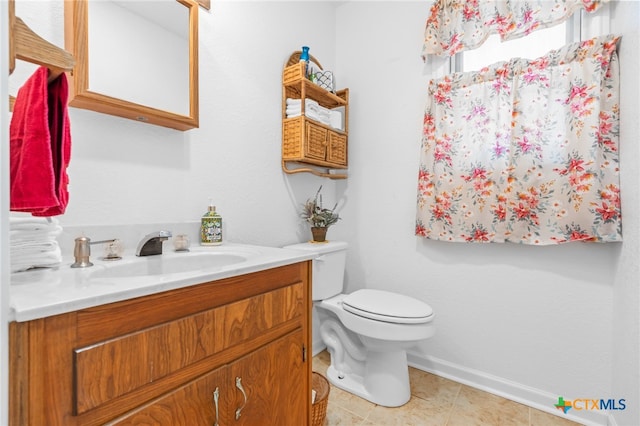 bathroom with toilet, vanity, and tile patterned floors