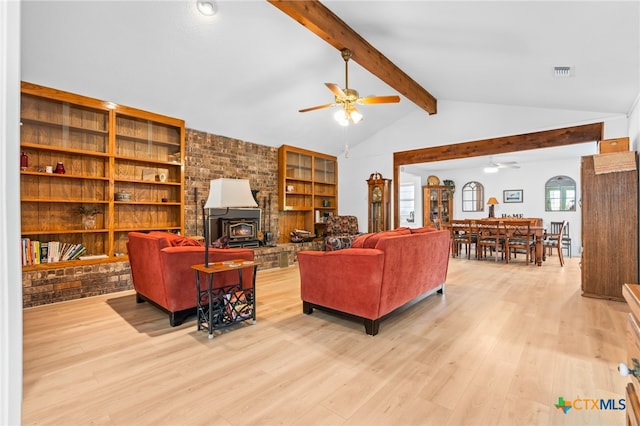 living room featuring a wood stove, light hardwood / wood-style floors, vaulted ceiling with beams, and ceiling fan