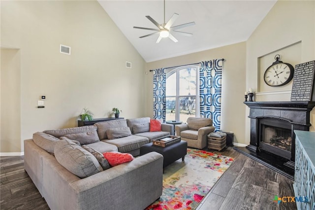 living area with ceiling fan, a fireplace with raised hearth, high vaulted ceiling, wood finished floors, and baseboards