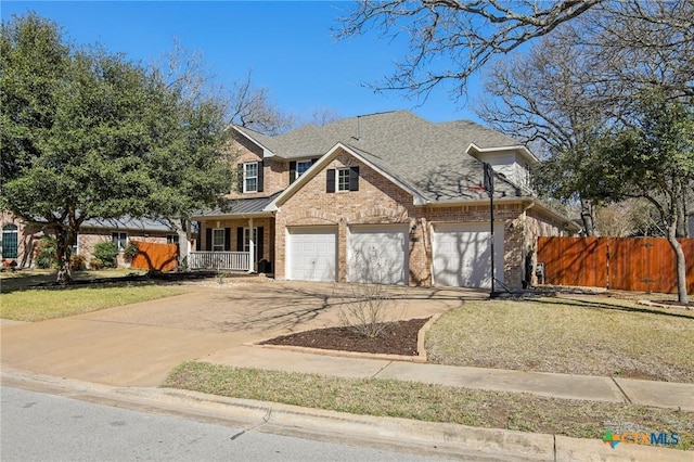 traditional-style home featuring concrete driveway, covered porch, an attached garage, a shingled roof, and brick siding