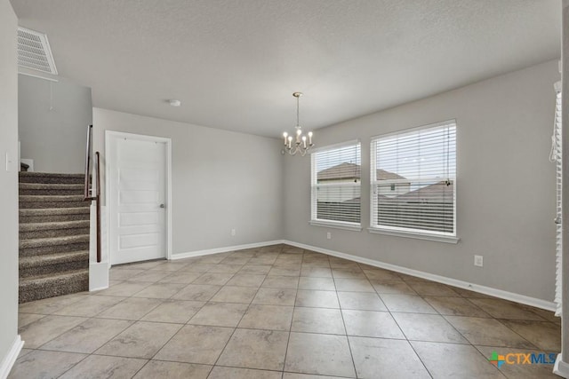 tiled empty room with an inviting chandelier