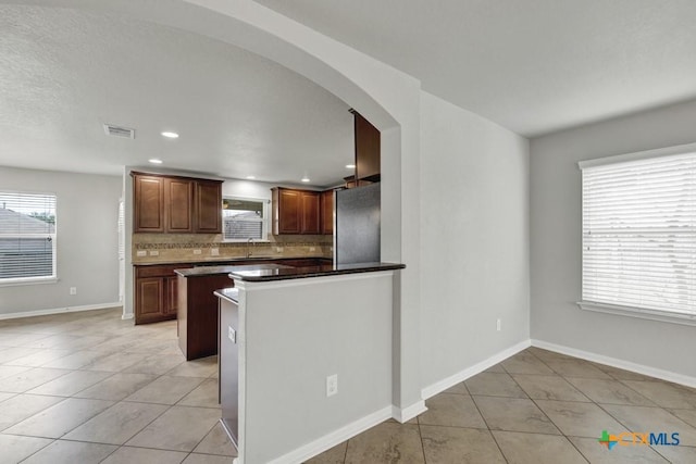 kitchen featuring stainless steel refrigerator, sink, tasteful backsplash, and a wealth of natural light