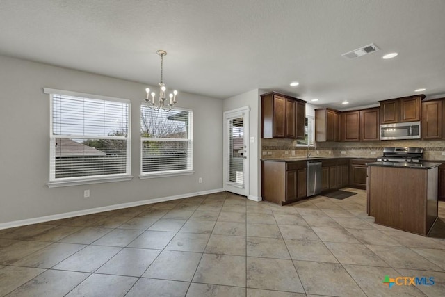 kitchen with light tile patterned floors, backsplash, hanging light fixtures, stainless steel appliances, and a chandelier