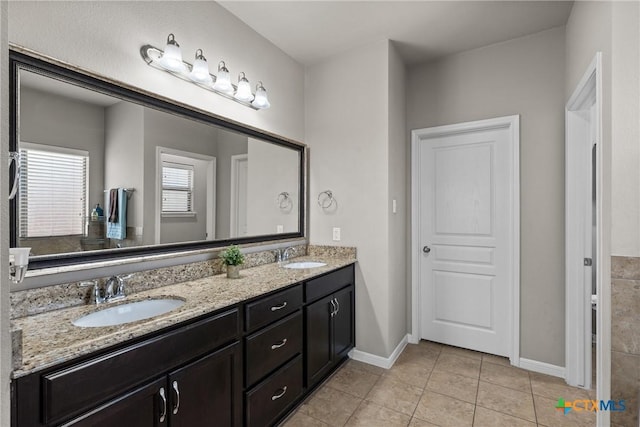 full bath with double vanity, tile patterned flooring, a sink, and baseboards