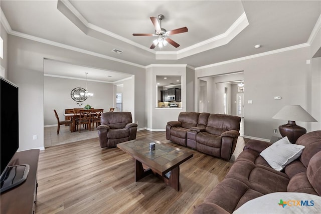 living room featuring ornamental molding, a tray ceiling, and wood finished floors