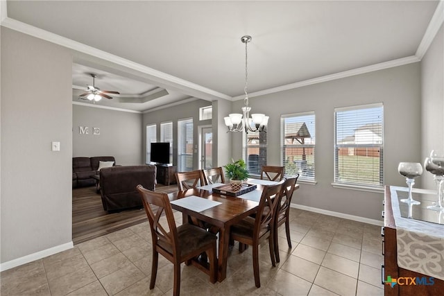 dining space featuring light tile patterned floors, baseboards, a tray ceiling, and crown molding