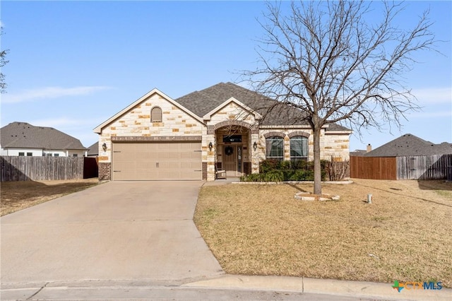 french provincial home with a garage, brick siding, fence, concrete driveway, and stone siding