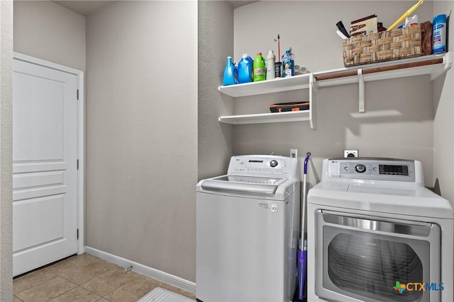 laundry area featuring laundry area, baseboards, light tile patterned flooring, and washing machine and clothes dryer