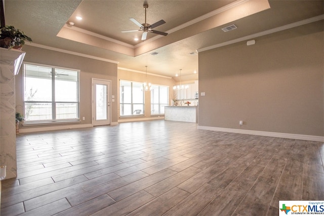 unfurnished living room with hardwood / wood-style flooring, ceiling fan with notable chandelier, crown molding, and a tray ceiling