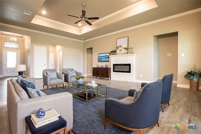 living room featuring hardwood / wood-style floors, a raised ceiling, ceiling fan, and crown molding