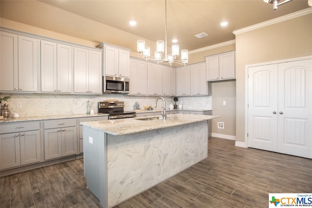 kitchen with sink, light stone counters, appliances with stainless steel finishes, a kitchen island with sink, and dark wood-type flooring