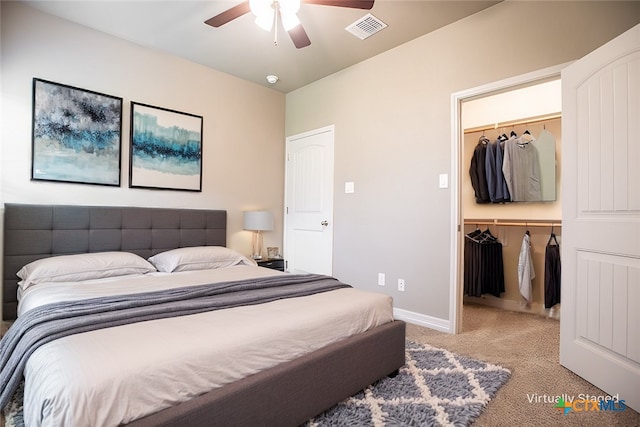 carpeted bedroom with ceiling fan, a walk in closet, and a closet