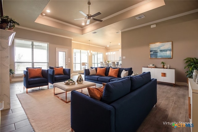 living room featuring ceiling fan with notable chandelier, a raised ceiling, dark hardwood / wood-style flooring, and ornamental molding