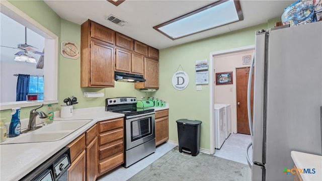 kitchen featuring stainless steel range with electric stovetop, sink, a skylight, washing machine and dryer, and fridge