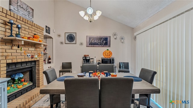 dining area with parquet flooring, a textured ceiling, an inviting chandelier, lofted ceiling, and a brick fireplace