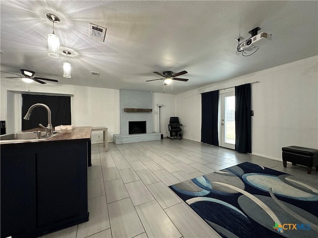 living room featuring ceiling fan, sink, and a brick fireplace