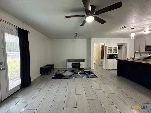 living room featuring ceiling fan, light hardwood / wood-style floors, and sink